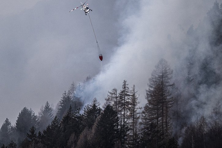 Six hélicoptères sont actuellement en action pour tenter de venir à bout des flammes. © KEYSTONE/TI-PRESS/Samuel Golay