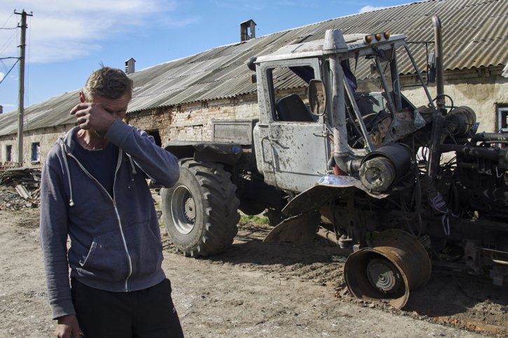 Un Ukrainien devant son tracteur détruit, près de Kharkiv. © KEYSTONE/EPA/SERGEY KOZLOV