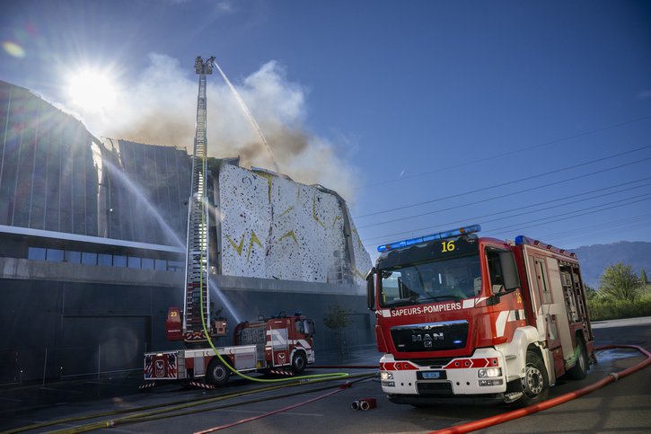 Les pompiers du Service d'incendie et de secours (SIS) interviennent sur un incendie dans une zone industrielle de Meyrin Satigny, ce dimanche 17 avril 2022 pres de Geneve. (KEYSTONE/Martial Trezzini) © KEYSTONE