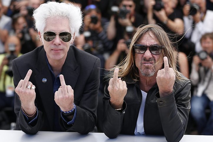 Le réalisateur américain Jim Jarmusch (G) et le chanteur américain Iggy Pop (D) font un doigt d'honneur aux photographes à Cannes en 2016 quand ils présentaient "Gimme Danger", un documentaire, consacré au groupe de rock, les Stooges. © KEYSTONE/EPA/JULIEN WARNAND