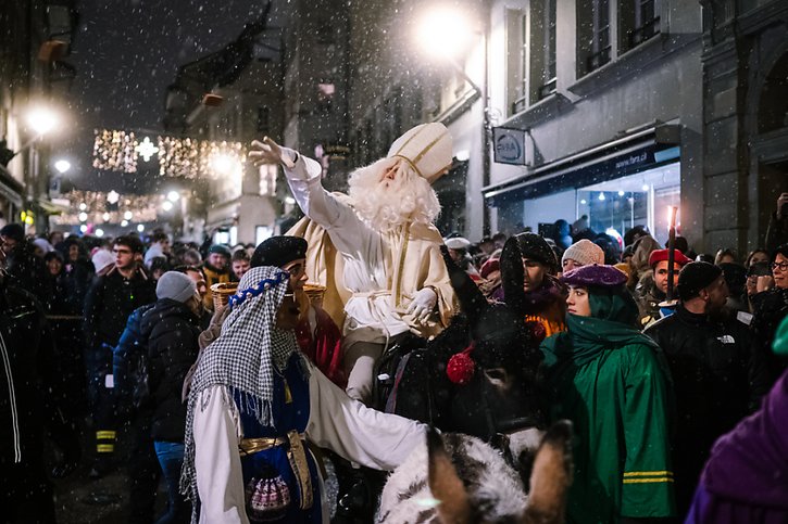 Durant son parcours en ville de Fribourg, Saint Nicolas, sur le dos de son fidèle âne Balou, a jeté des pains d'épices à la foule accourue le voir. © KEYSTONE/ADRIEN PERRITAZ
