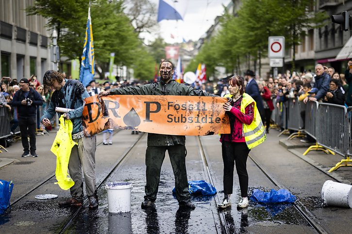 Des activistes de "Drop Fossil Subsidies" ont manifesté lundi pendant le cortège du Sechseläuten à Zurich. Ils se sont aspergés d'un liquide noir pour protester contre les énergies fossiles. © KEYSTONE/MICHAEL BUHOLZER